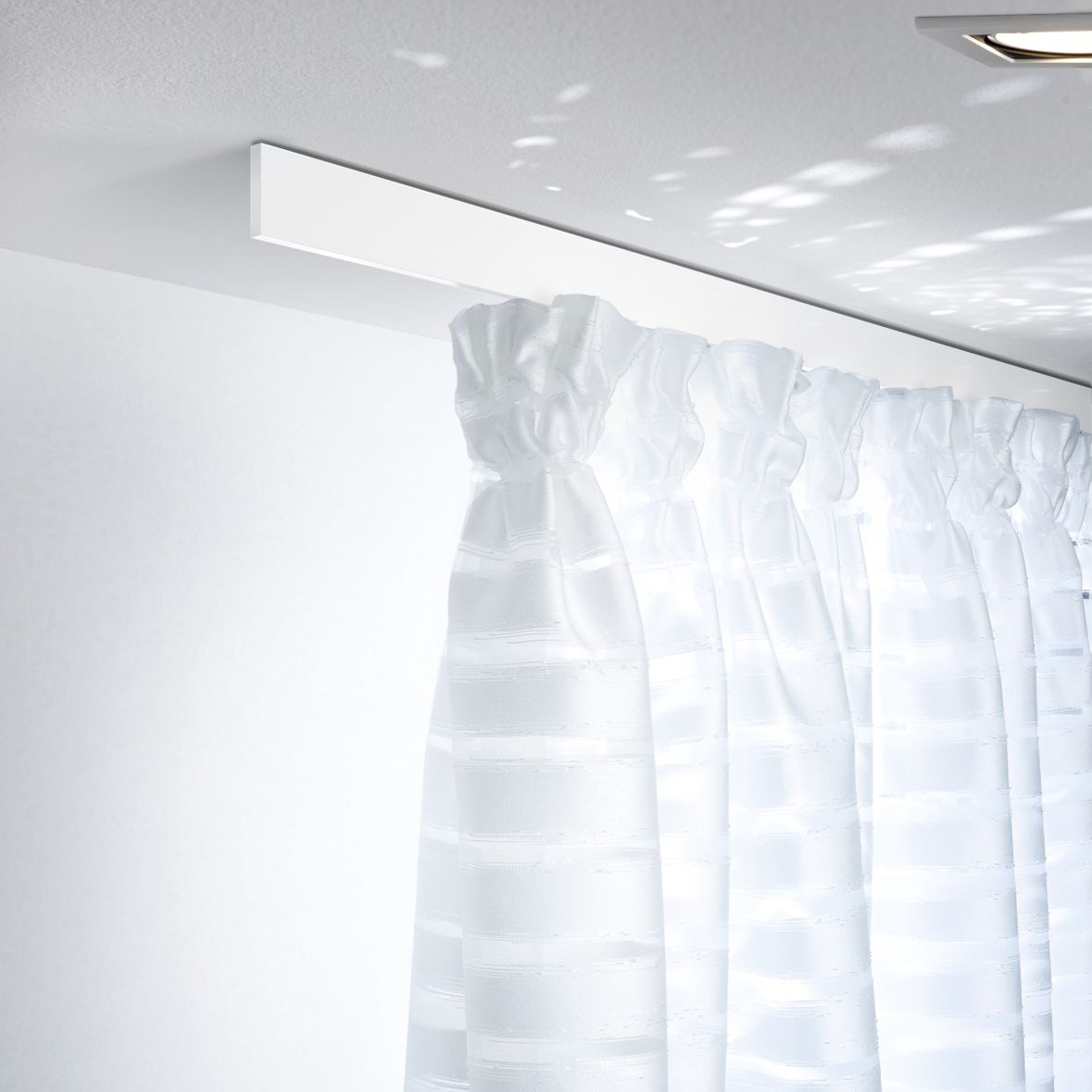 Puristisches Interstil Schienensystem „Helix“ in mattem Weiß, bündig an einer weißen Decke montiert. Die extrem flache, rechteckige Vorhangschiene trägt einen weißen, halbtransparenten Vorhang mit Querstreifen-Struktur, der in dekorativen Falten fällt. Das Bild betont eine helle, lichtdurchflutete Atmosphäre mit sanften Lichtreflexionen an der Decke.