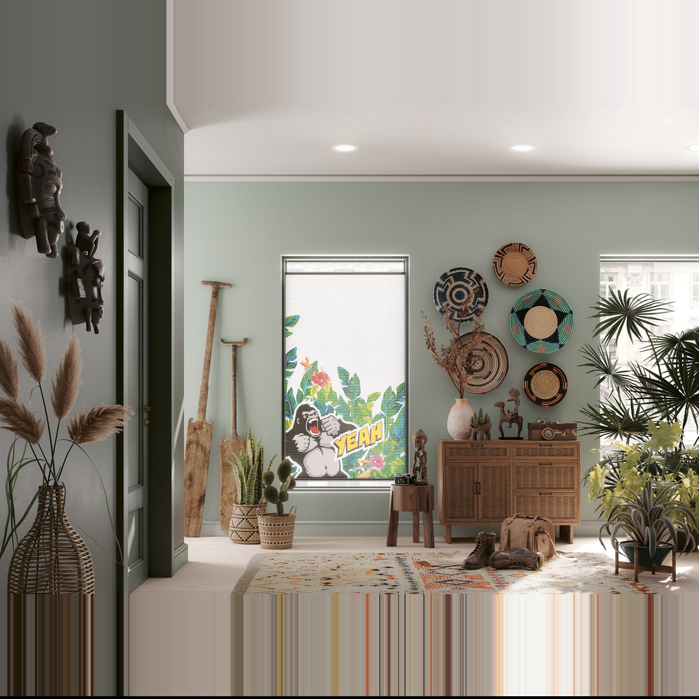 „Ein modernes Wabenplissee aus der MHZ-Kollektion 'sieger design' mit dem Muster 'Marvellous Monkey'. Das hellgraue Plissee zeigt ein dezentes, grafisches Affen-Motiv und ist mittig an einem hohen Fenster positioniert, wodurch oben und unten Tageslicht einfällt.